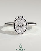 Kynora CJ statement 2-carat oval bezel solitaire engagement ring with open cathedral high setting, showcasing elegant jewelry design.