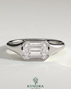 Kynora CJ 2ct emerald east-west bezel solitaire engagement ring with signet band showcasing a vibrant green emerald gemstone.