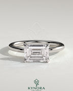 Kynora CJ 2ct emerald East-West claw solitaire engagement ring featuring a vibrant green emerald gemstone set horizontally.