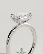 Kynora CJ 2-carat emerald cut east-west claw solitaire engagement ring with a central emerald gemstone and sleek band.