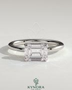 Kynora CJ 2ct emerald cut east-west claw solitaire engagement ring with hidden halo and sleek gold band.