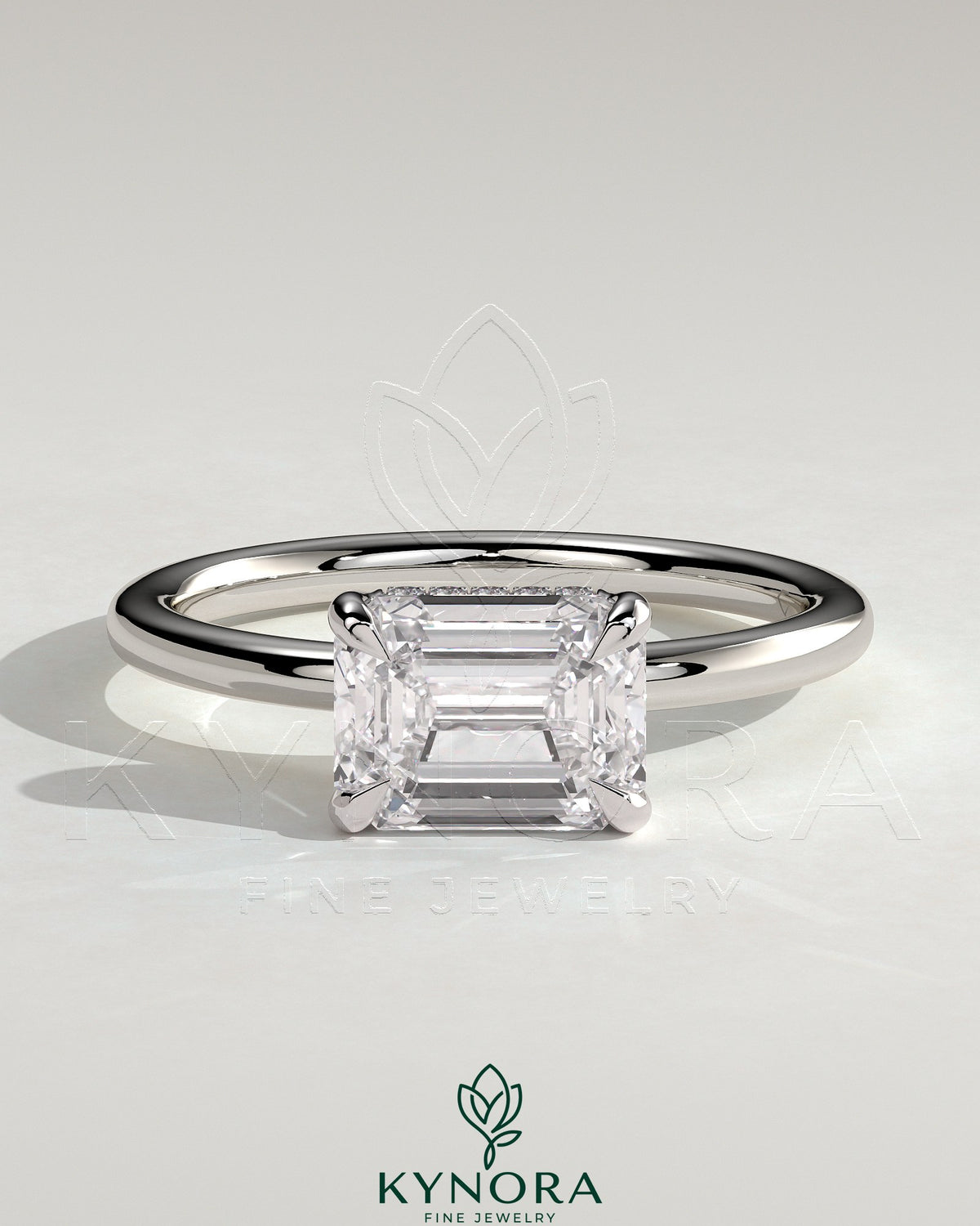 Kynora CJ 2ct emerald cut east-west claw solitaire engagement ring with hidden halo and sleek gold band.