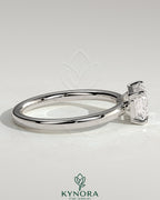 Kynora CJ 2ct emerald east-west claw solitaire engagement ring with raised basket gallery featuring a central emerald gemstone.