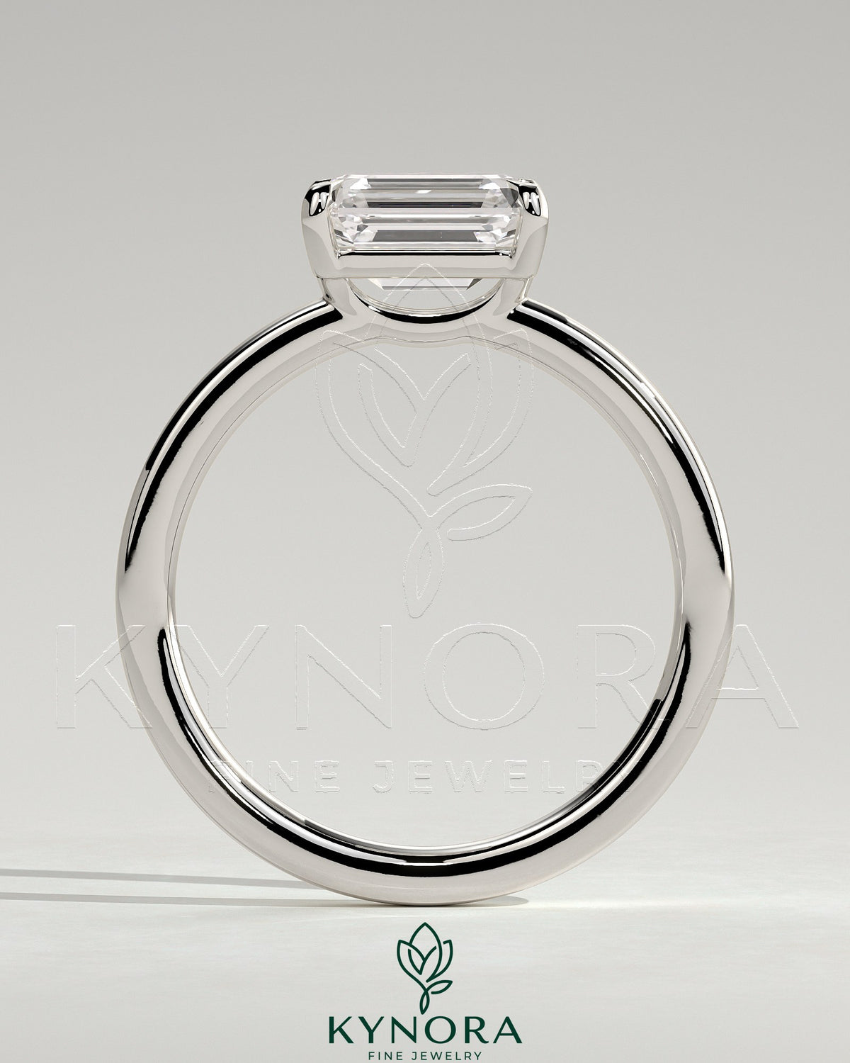 Kynora CJ 2ct emerald east-west claw solitaire engagement ring with raised basket gallery showcasing a vibrant emerald gemstone.