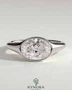 Kynora CJ 2ct oval east-west bezel solitaire engagement ring with signet band, featuring a central diamond and sleek gold design.