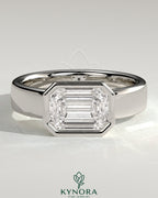 Kynora CJ statement 2ct emerald east-west bezel solitaire engagement ring with flat cigar band, featuring a prominent green emerald gemstone.