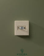 Kynora CJ statement 2ct emerald east-west bezel solitaire engagement ring with flat cigar band, featuring a prominent emerald stone.