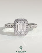 Kynora CJ 2ct emerald cut solitaire halo engagement ring with pave band, showcasing a sparkling emerald gemstone and intricate design.