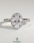 Kynora CJ 2ct oval claw solitaire engagement ring with halo and pave band, showcasing sparkling diamond details.