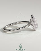 Kynora CJ 2ct oval claw solitaire engagement ring with halo of small diamonds, featuring a sleek gold band.