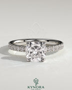Kynora CJ 2ct cushion claw solitaire engagement ring with hidden halo and pavé band, showcasing elegant diamond design.
