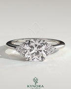 Kynora CJ 2-carat cushion claw solitaire engagement ring with round shoulder stones, featuring a sparkling central diamond and elegant design.