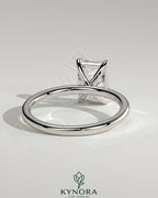 Kynora CJ 2-carat emerald claw solitaire engagement ring featuring a bright emerald-cut center stone and a sleek band.