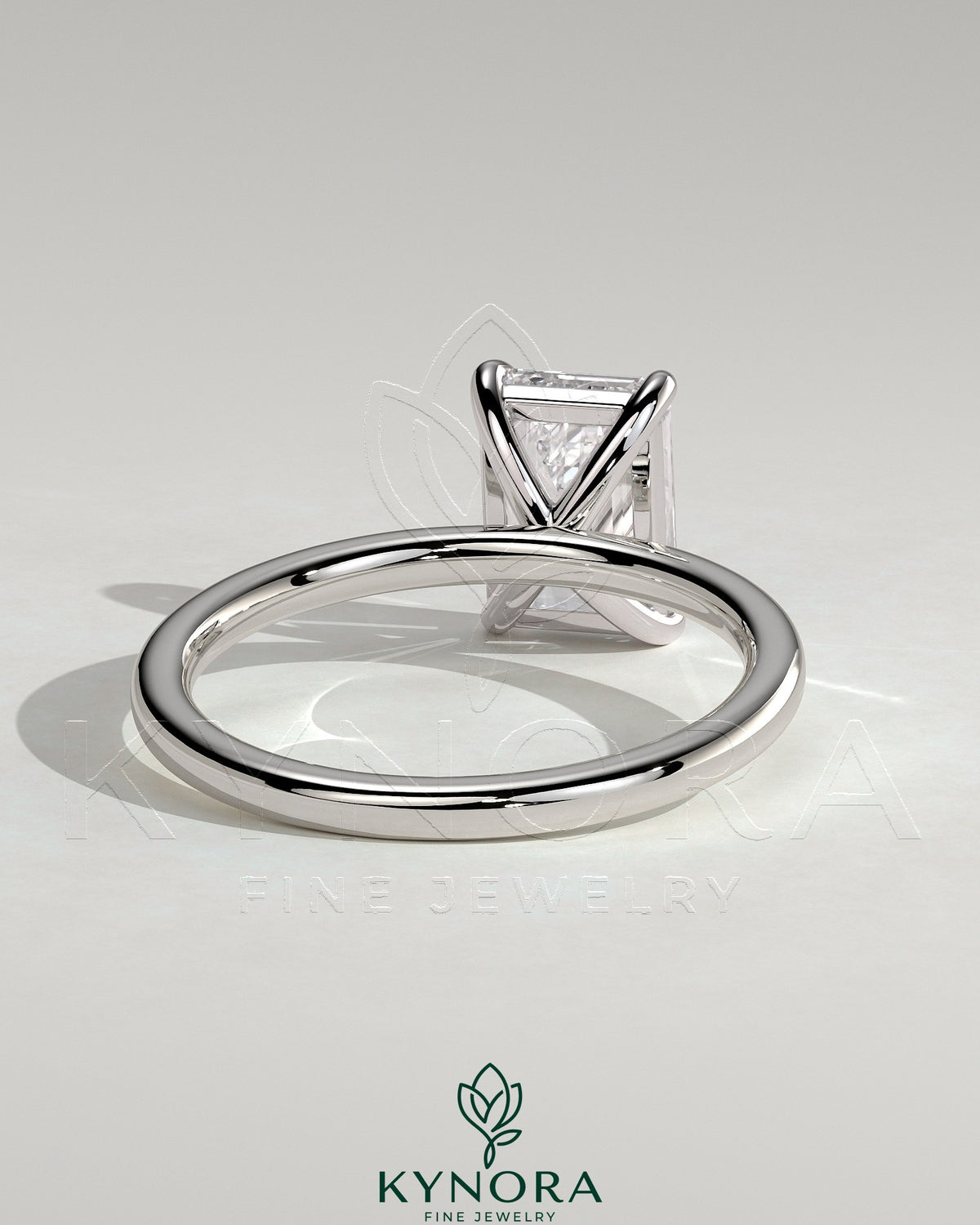 Kynora CJ 2-carat emerald claw solitaire engagement ring featuring a bright emerald-cut center stone and a sleek band.