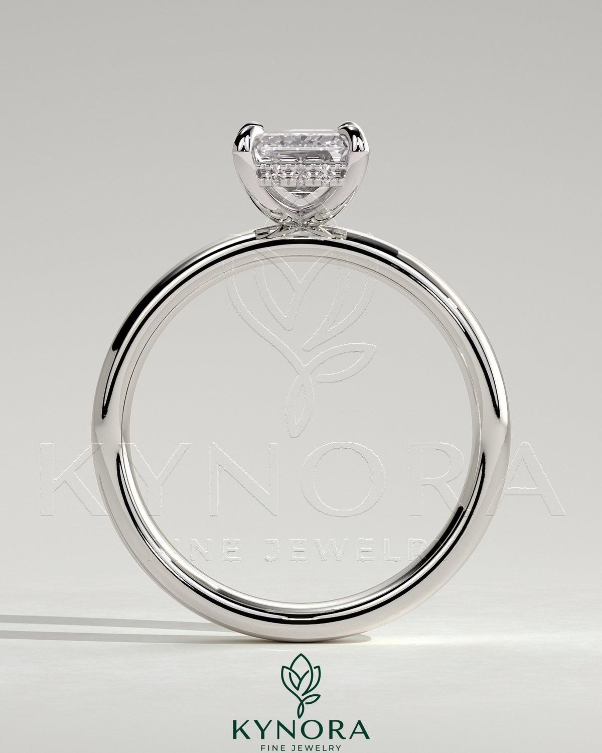 Kynora CJ 2ct emerald claw solitaire engagement ring with cigar band and hidden halo, featuring a sparkling emerald gemstone.