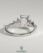 Kynora CJ 2ct emerald claw solitaire engagement ring with clustered round shoulder stones, showcasing elegant jewelry craftsmanship.