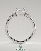 Kynora CJ 2ct emerald claw solitaire engagement ring with clustered round shoulder stones, elegant and sparkling jewelry design.