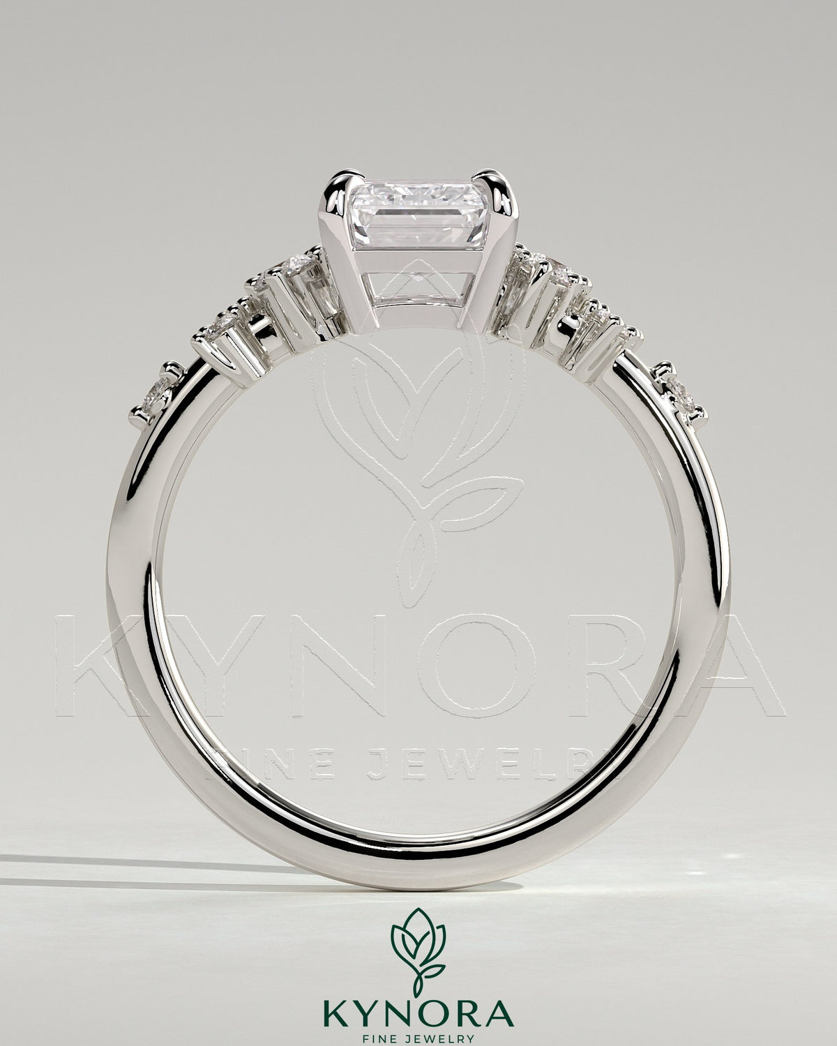 Kynora CJ 2ct emerald claw solitaire engagement ring with clustered round shoulder stones, elegant and sparkling jewelry design.