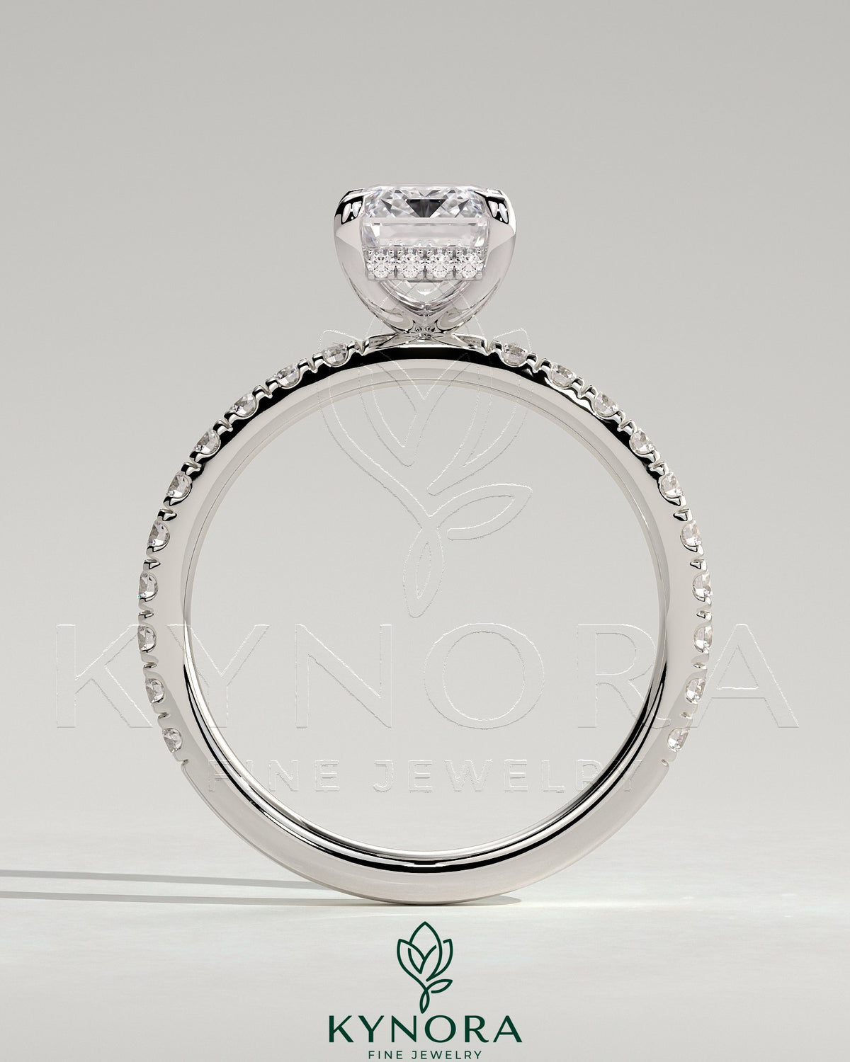 Kynora CJ 2ct emerald claw solitaire engagement ring with hidden halo and pavé band, showcasing intricate design and sparkling gemstone.
