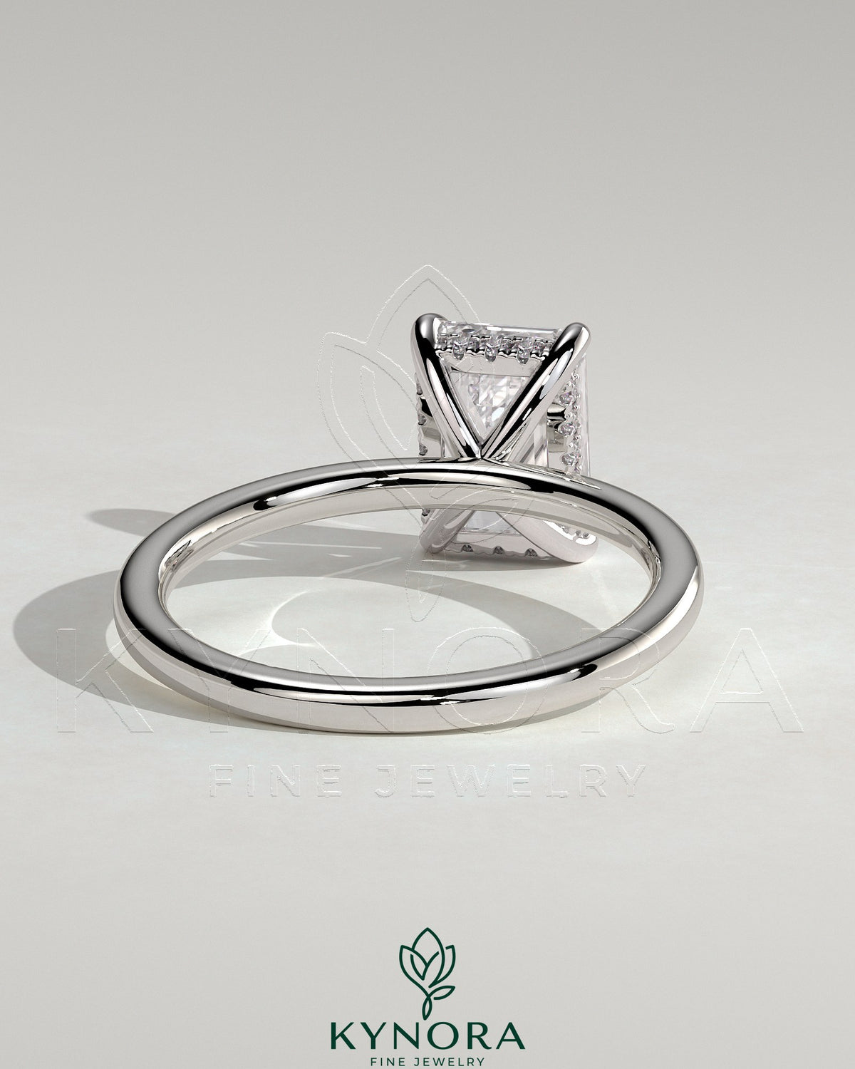 Kynora CJ 2ct emerald claw solitaire engagement ring with hidden halo, featuring a central emerald-cut gemstone and intricate design.