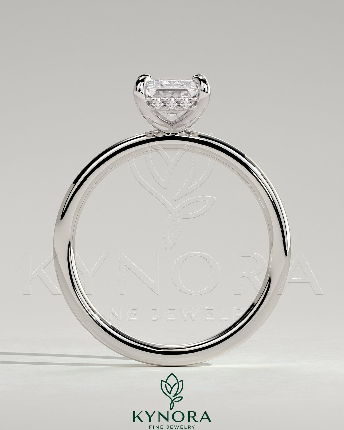 Kynora CJ 2ct emerald claw solitaire engagement ring with hidden halo, featuring a central emerald-cut gemstone and intricate band details.