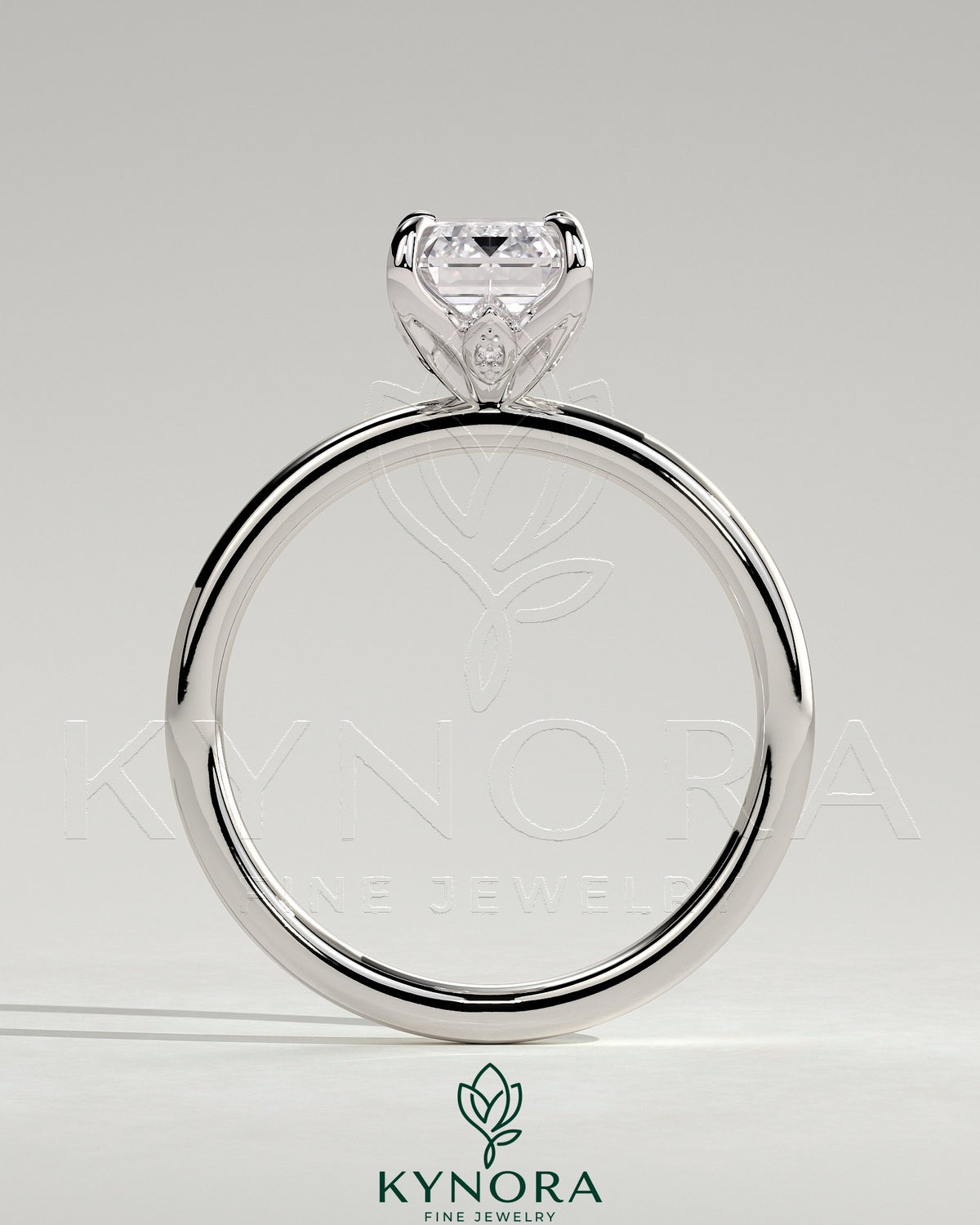 Kynora CJ 2ct emerald claw solitaire engagement ring with petal gallery and accent leaf details, showcasing intricate design and sparkling gemstone.