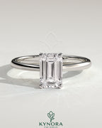 Kynora CJ 2ct emerald claw solitaire engagement ring with tapered band and cathedral low setting, featuring a sparkling emerald gemstone.