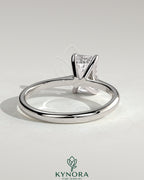 Kynora CJ 2ct emerald solitaire engagement ring with tapered band and cathedral low setting, showcasing elegant jewelry design.