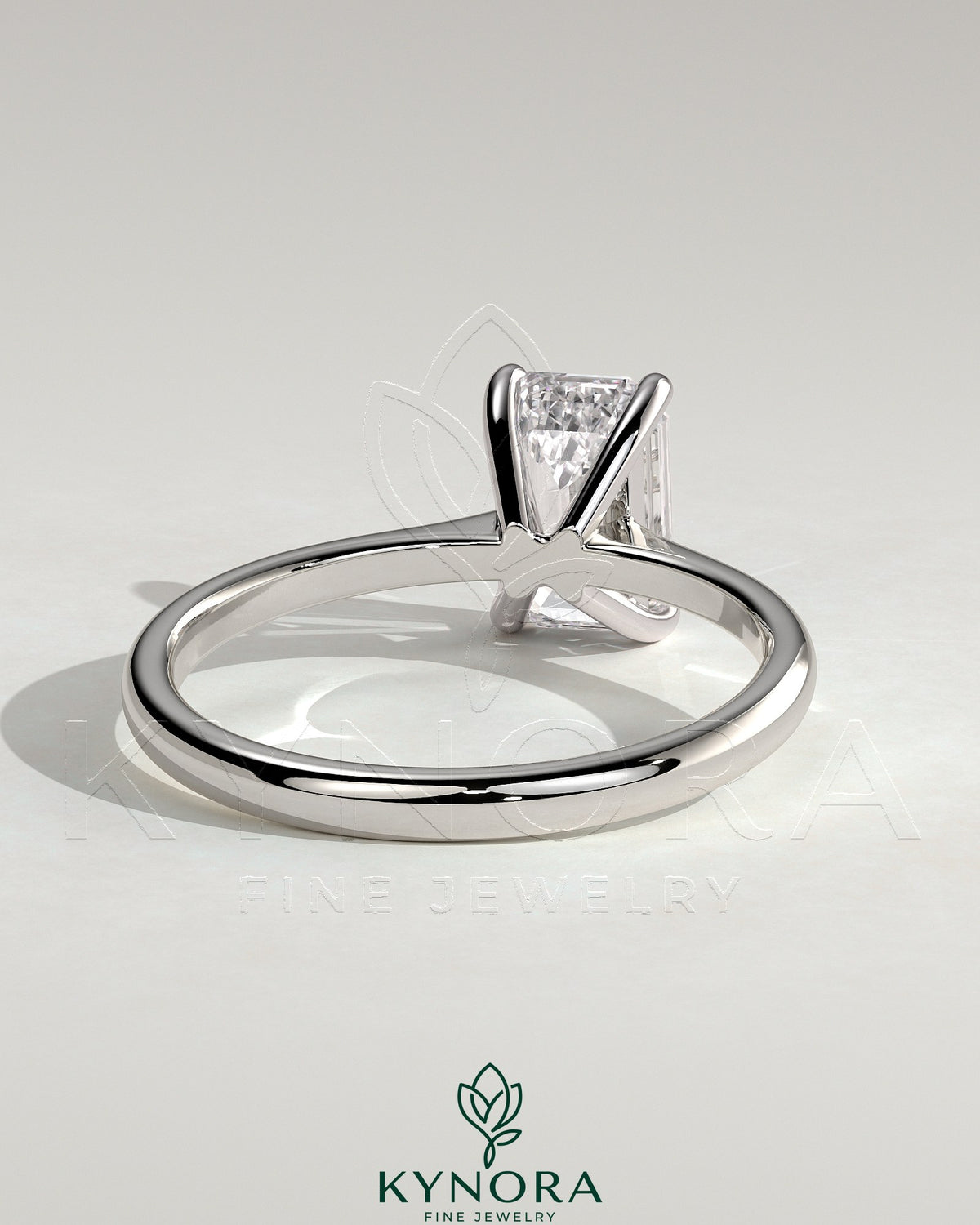 Kynora CJ 2ct emerald solitaire engagement ring with tapered band and cathedral low setting, showcasing elegant jewelry design.