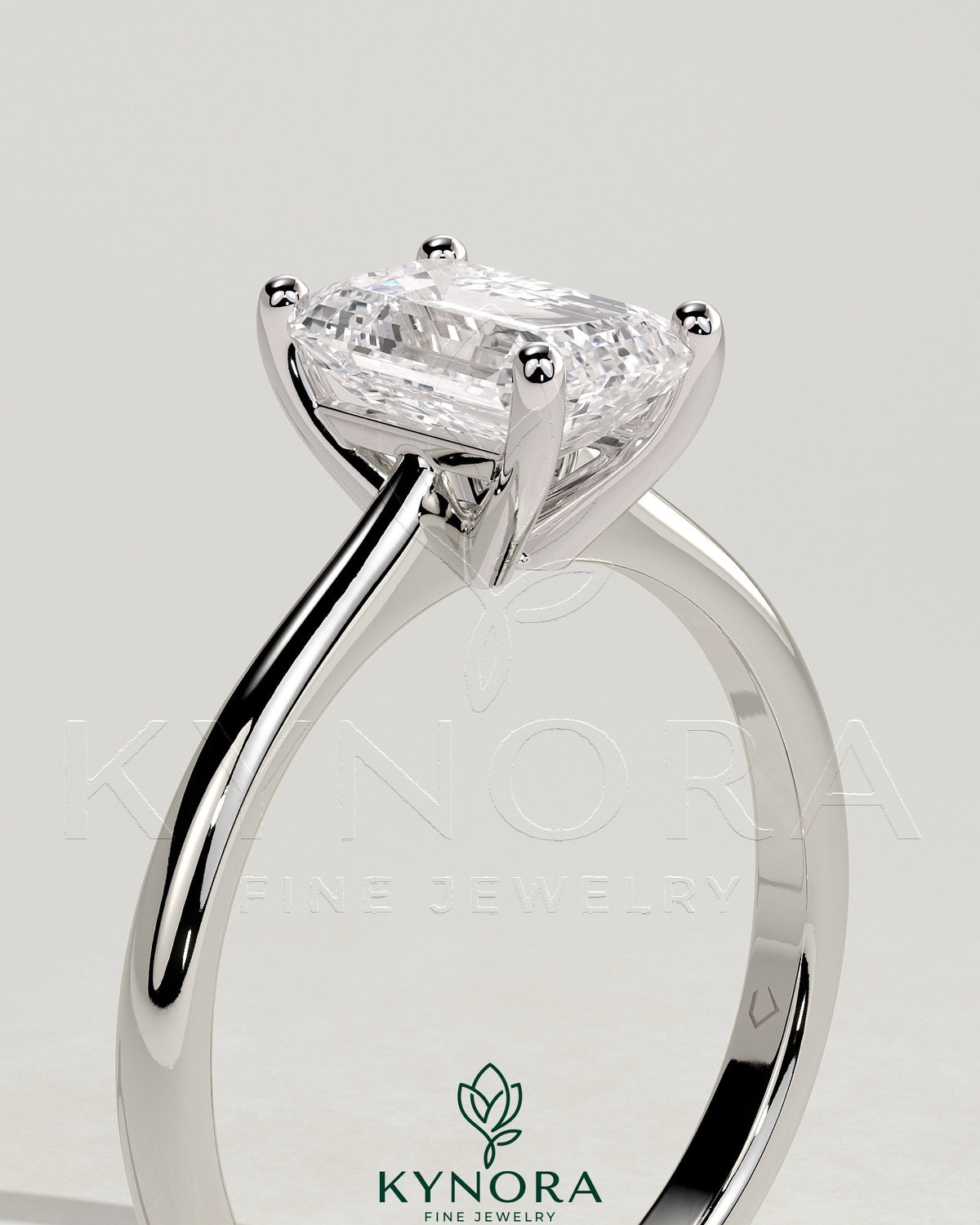 Kynora CJ 2ct emerald claw solitaire engagement ring with tapered band and cathedral low setting, showcasing a sparkling emerald gemstone.