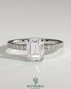 Kynora CJ 2ct emerald claw solitaire engagement ring with wrap-around hidden halo and pave band, showcasing a dazzling center stone.