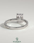 Kynora CJ 2ct emerald claw solitaire engagement ring with wrap-around hidden halo and pave band, showcasing intricate design and sparkle.