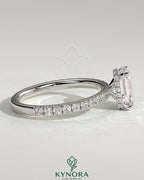 Kynora CJ 2ct emerald claw solitaire engagement ring with wrap-around hidden halo and pave band, showcasing detailed craftsmanship.