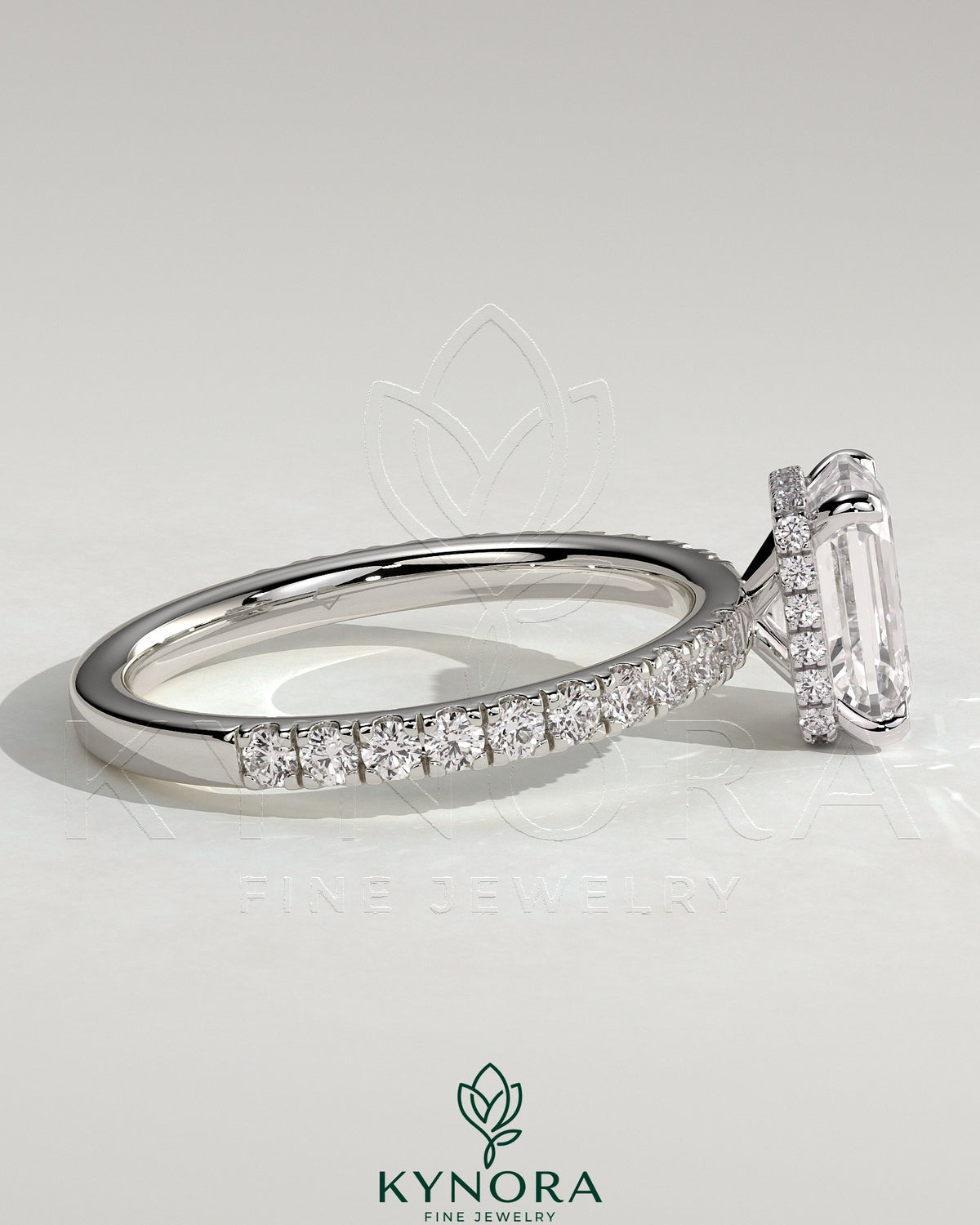 Kynora CJ 2ct emerald claw solitaire engagement ring with wrap-around hidden halo and pave band, showcasing detailed craftsmanship.