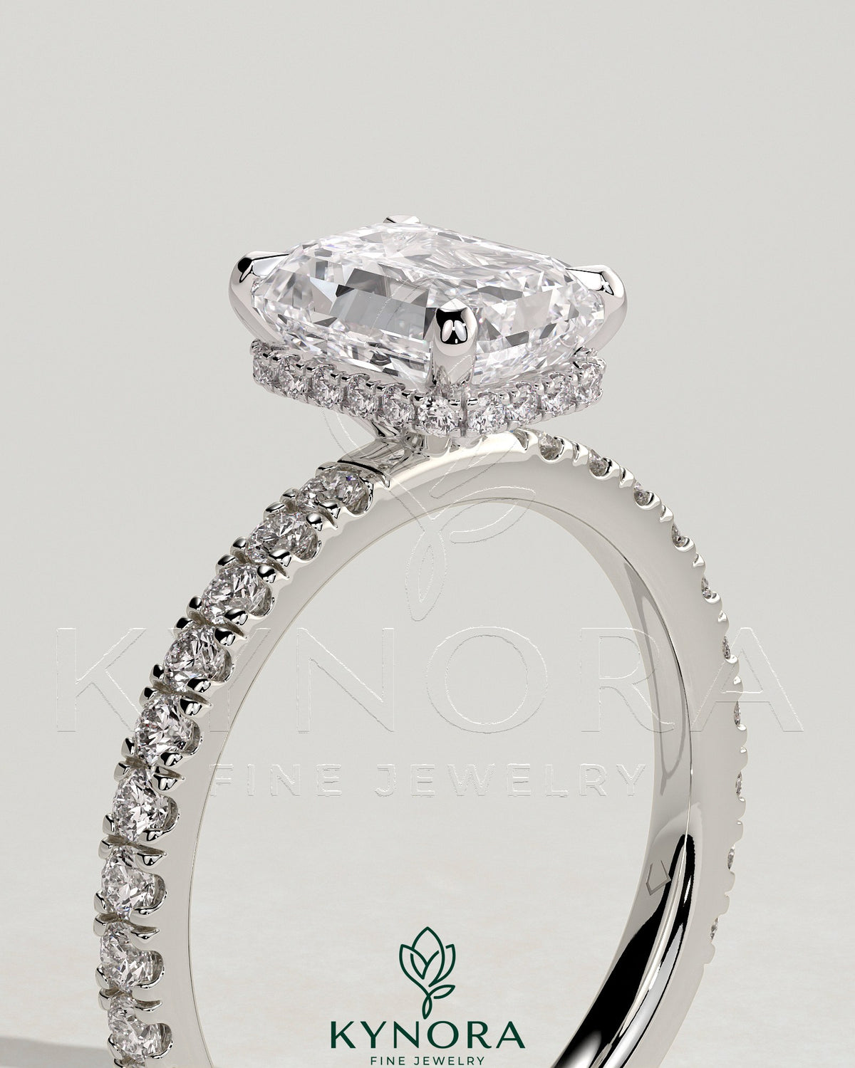 Kynora CJ 2ct emerald claw solitaire engagement ring with wrap-around hidden halo and pave band, showcasing intricate design.