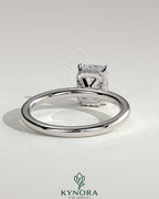 Kynora CJ 2ct emerald claw solitaire engagement ring with wrap-around hidden halo, featuring a sparkling central emerald gemstone.