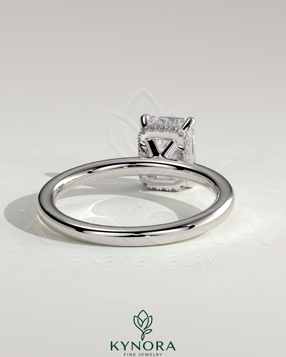 Kynora CJ 2ct emerald claw solitaire engagement ring with wrap-around hidden halo, featuring a sparkling central emerald gemstone.