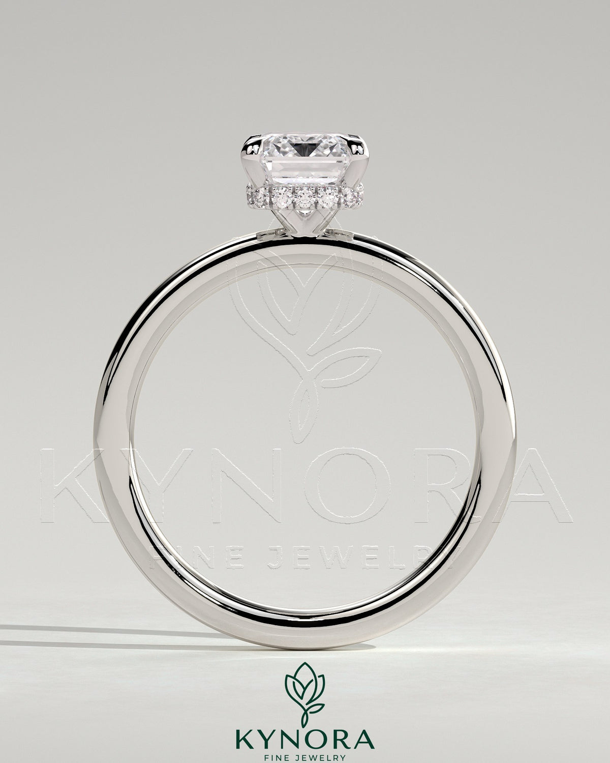Kynora CJ 2ct emerald claw solitaire engagement ring with a wrap-around hidden halo in gold, featuring a central emerald cut gemstone.