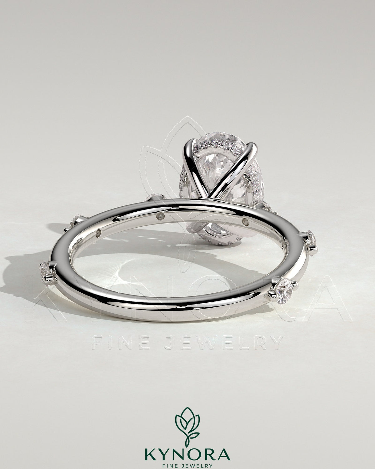 Kynora CJ 2ct oval claw solitaire engagement ring with six round accent stones and a hidden halo design.