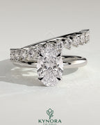 Kynora CJ 2-carat oval claw solitaire engagement ring with double plain and round accent stones band, crafted in elegant jewelry style.