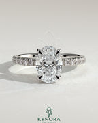 Kynora CJ 2ct oval claw solitaire engagement ring with hidden halo and pave band, showcasing a sparkling central diamond.