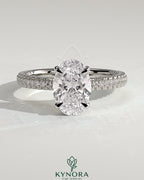 Kynora CJ 2ct oval claw solitaire engagement ring with hidden halo and triple pave band, showcasing sparkling diamond details.