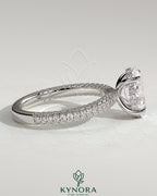 Kynora CJ 2ct oval claw solitaire engagement ring with hidden halo and triple pave band, showcasing elegant diamond setting.