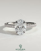 Kynora CJ 2ct oval claw solitaire engagement ring with hidden halo, pave band, and cathedral high setting, showcasing elegant jewelry design.