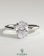Kynora CJ 2ct oval claw solitaire engagement ring with wrap-around hidden halo design, showcasing elegant diamond setting.