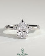 Kynora CJ 2ct pear-shaped solitaire engagement ring with six round accent stones and hidden halo design.
