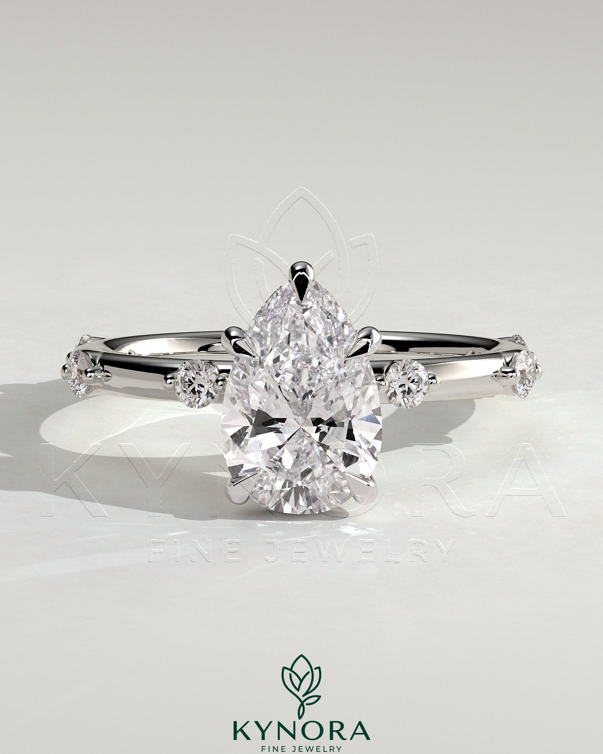 Kynora CJ 2ct pear-shaped solitaire engagement ring with six round accent stones and hidden halo design.