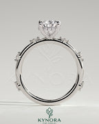 Kynora CJ 2ct pear-shaped solitaire engagement ring with six round accent stones and a hidden halo design.