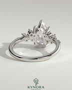Kynora CJ 2ct pear-shaped diamond solitaire engagement ring with clustered round shoulder stones in a sleek platinum setting.