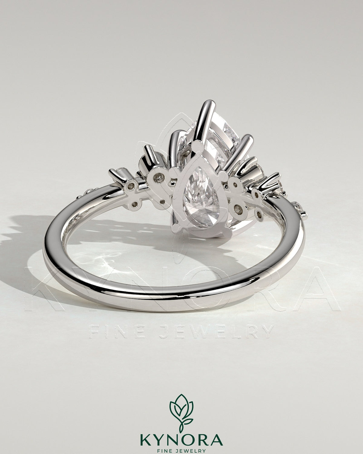 Kynora CJ 2ct pear-shaped diamond solitaire engagement ring with clustered round shoulder stones in a sleek platinum setting.